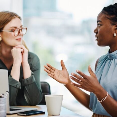 Two young professional women talking over a laptop