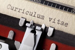 Close up on a typewriter that’s typed curriculum vitae on a piece of paper.