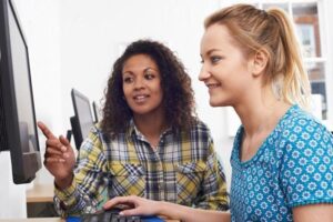 Two young businesswomen, one of which is a candidate, looking at a computer in an office.