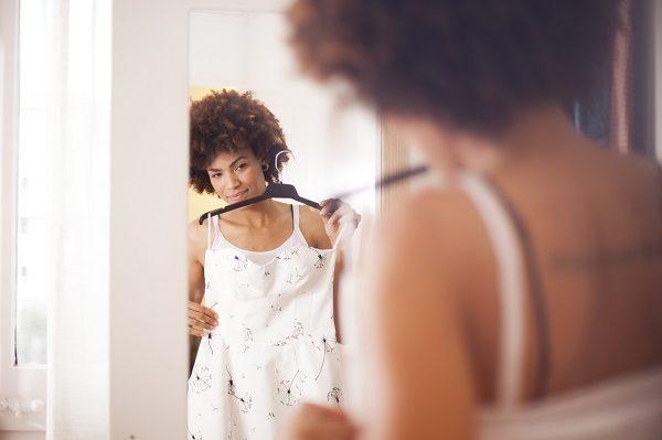 A woman trying on a white dress for an interview while looking in the mirror.