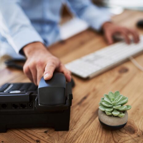 Cropped shot of a man holding the receiver of a telephone at work