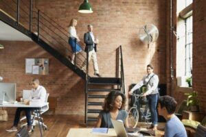 An open plan office with exposed brick walls and colleagues working in groups, symbolising a positive work culture.