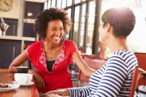 An interview with a hiring manager and a candidate in an open plan office, smiling and laughing with each other.