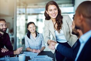 A hiring manager smiling and greeting and interviewee in an office.