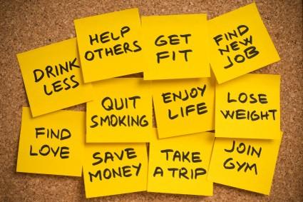 Eleven yellow post-it notes with a cork board with common New Year’s resolutions.