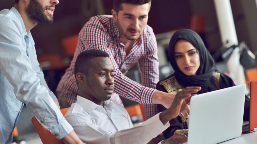 Four workers in Dubai looking at a computer screen