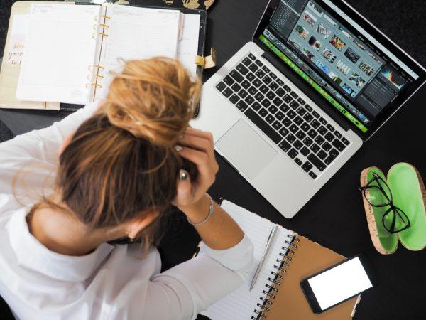 Woman with her head in her hands next to a laptop