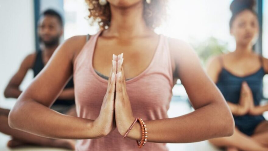 A woman sits in a yoga class in a peaceful pose