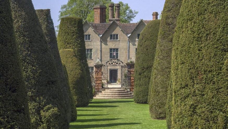 Country house with hedges leading up to the front door.