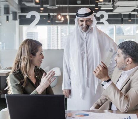 A group of three human resources professionals discussing business strategy and decisions in modern office in the Middle East.
