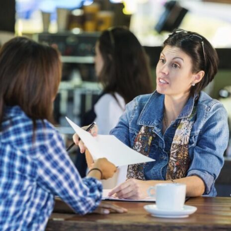 Two women having an interview and sitting at a table in a cafe