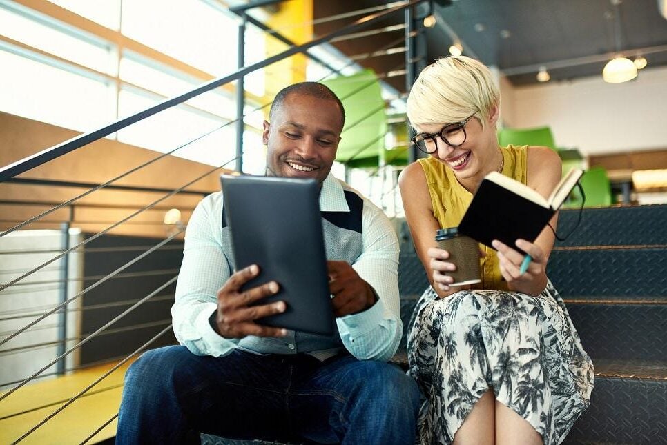 Team of young casual business people collaborating on an online project using a digital touchpad tablet computer in a bright modern office space. Serie with light flares