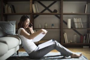 Young woman talking on the smartphone while watching the documents.
