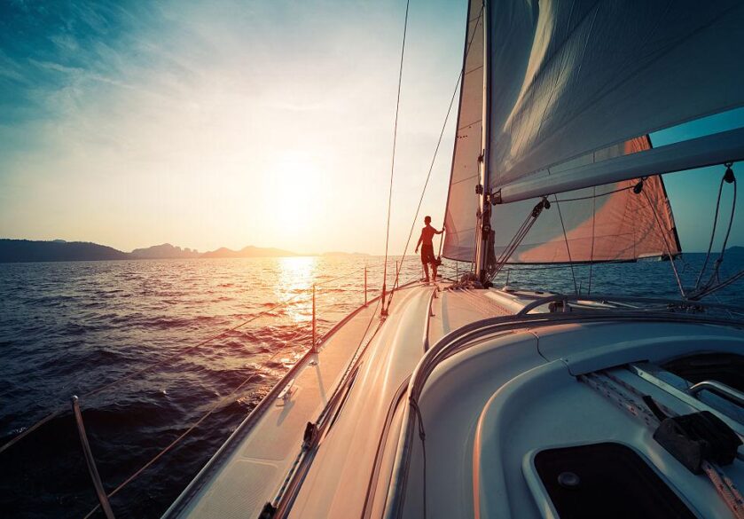 A view of the sun setting on the horizon, taken from the deck of a luxury yacht.