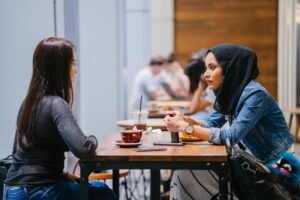 Two women talk over a table at a cafe