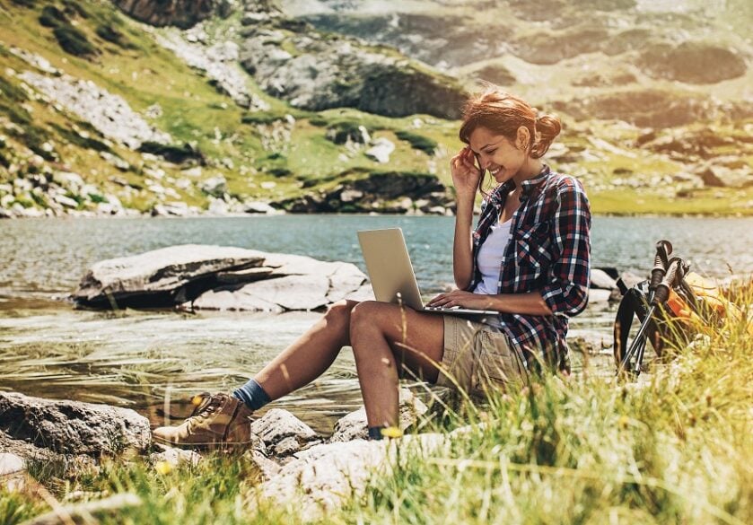 Remote working female sits outside on laptop