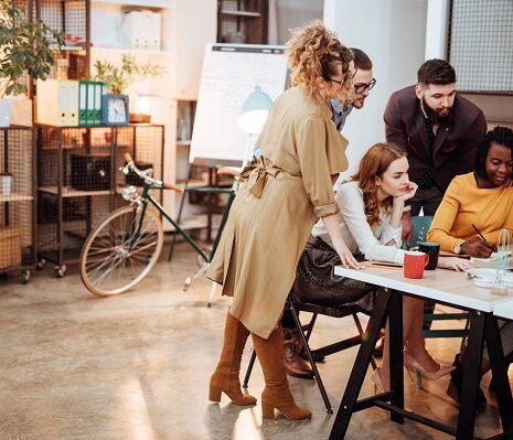 A small group of five human resources professionals have a quick impromptu meeting in a creative, contemporary office space.
