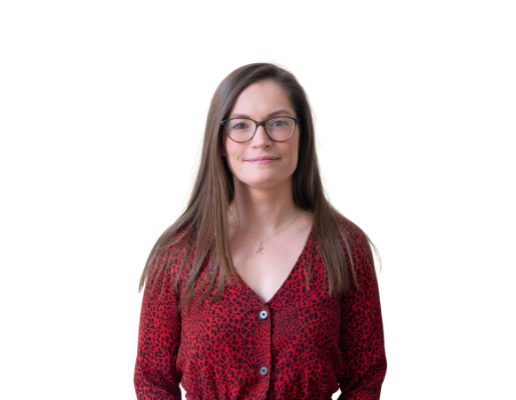 Katie, wearing a red leopard print cardigan and glasses, with brown hair, is smiling at the camera
