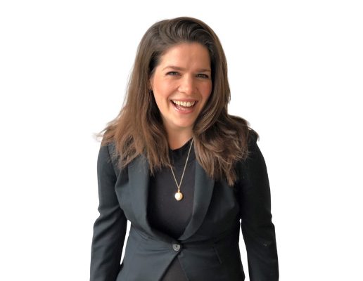 Rosanna, a woman wearing a black blazer with long brown hair, is laughing