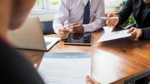 A photo of colleagues at a table with a resume and Apple products