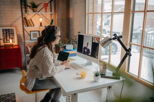 Woman working at a home desk on a video call with a colleague