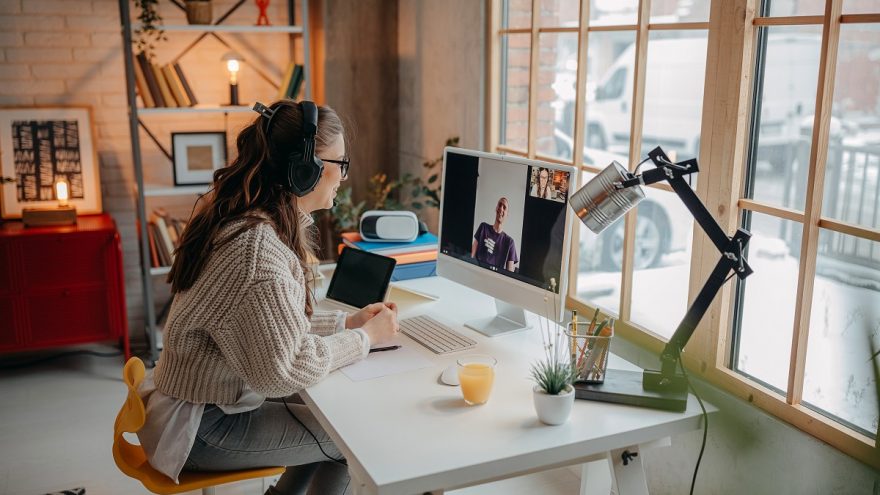 Woman working at a home desk on a video call with a colleague