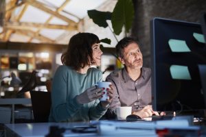 Colleagues sitting together at a computer, observing the content of the screen.