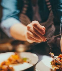 Close up of the hands of a chef preparing a dish.