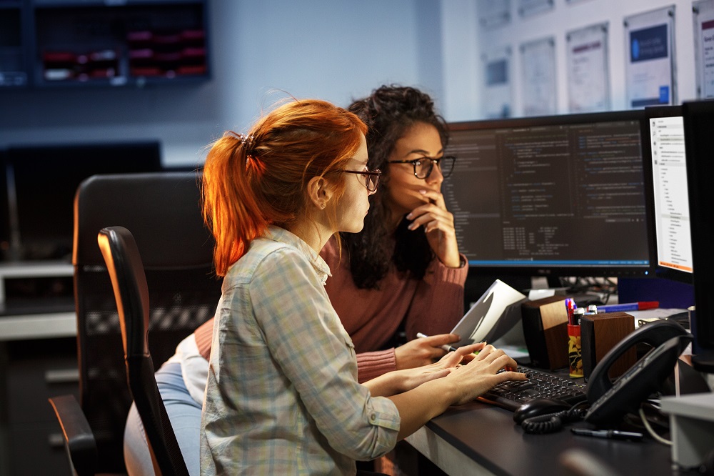 Two women working on a programming project in an office.