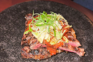 A photo of a meat dish with a salad serving placed on top.