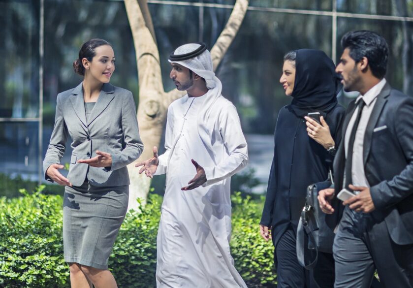A group of middle eastern business people walking and talking outside on a Dubai city street.