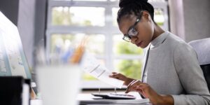 Woman updating document with a calculator