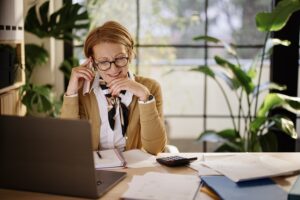 Woman sitting at desk in front of a computer on a phone call