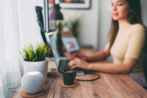A photo of a lady typing at her laptop alongside a mug of tea