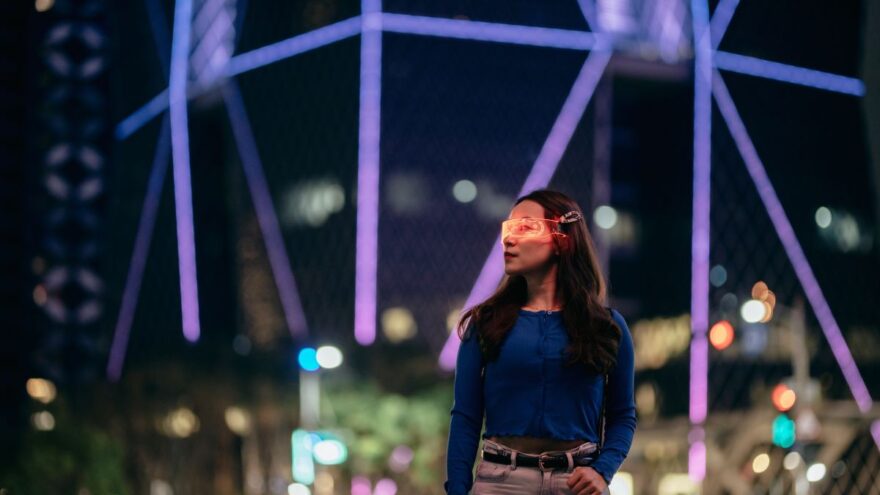 A woman wearing AI glasses at night in a futuristic cityscape.