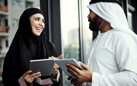 Cropped shot of two young businesspeople dressed in Islamic traditional clothing using their tablets on the office balcony