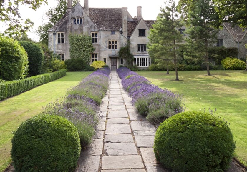 An old stately house with mature grounds on a summers day in the English countryside.