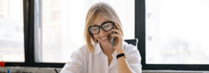 Lady dressed in corporate attire on the phone taking notes