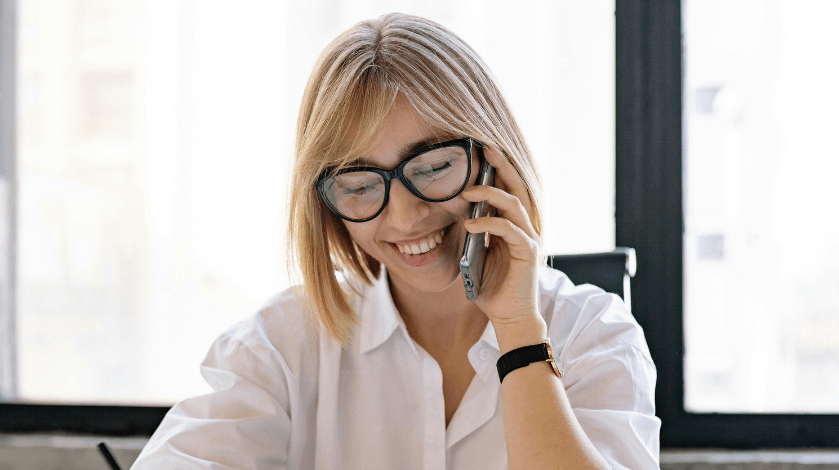 Lady dressed in corporate attire on the phone taking notes