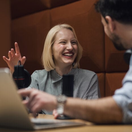 Woman speaking to man in office in front of voice recording equipment