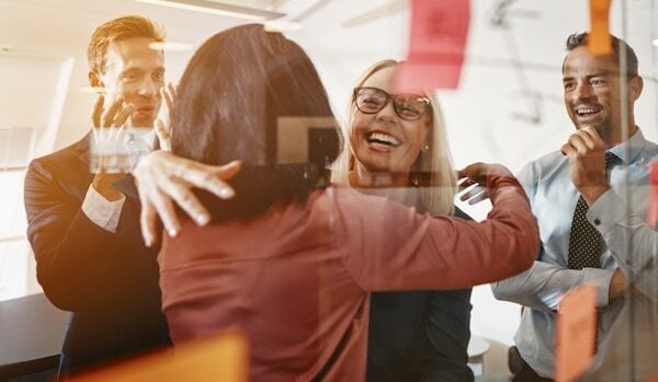 Businesswomen hugging while brainstorming with their team in an office