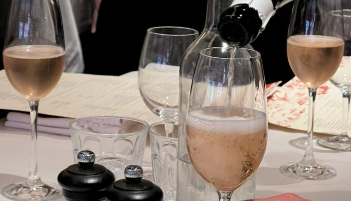 Image of four champagne flutes with a pouring bottle